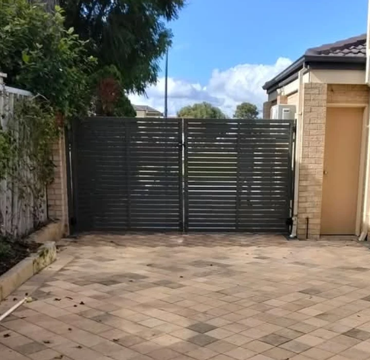 Charcoal horizontal slat double gates across a paved driveway, a Brenton Harvey project